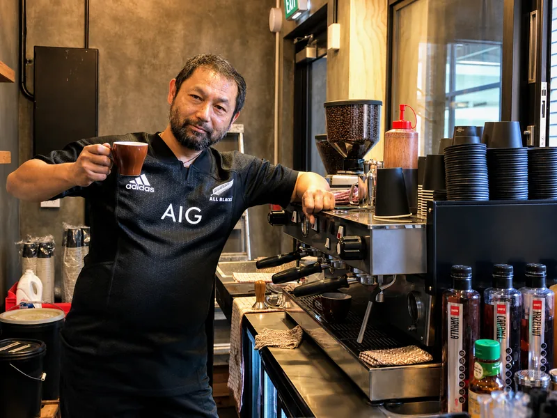 A barista holding coffee beside the espresso machine